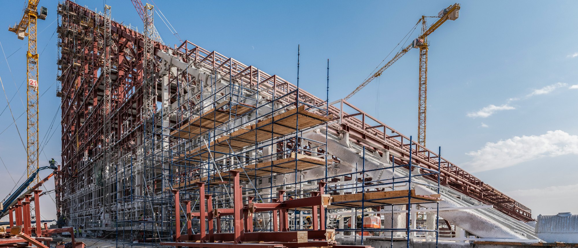 A steel-framed structure under construction, wrapped in scaffolding